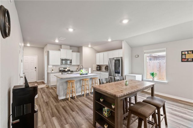 7706 Iron Man, Corpus Christi, TX 78414 - kitchen featuring tasteful backsplash, lofted ceiling, appliances with stainless steel finishes, white cabinets, and an island with sink