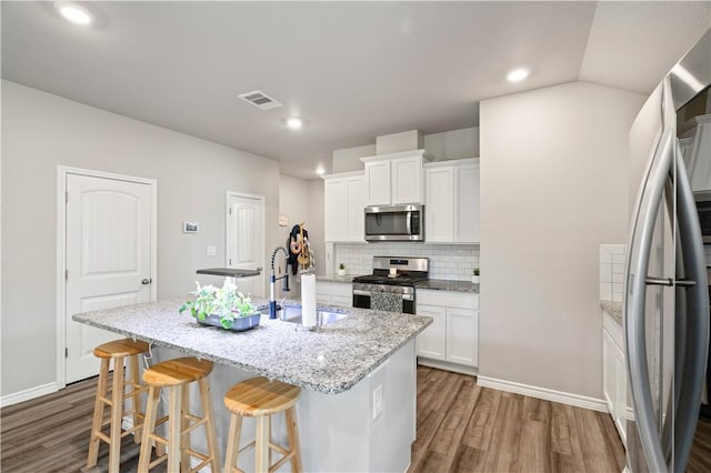 7706 Iron Man, Corpus Christi, TX 78414 - kitchen featuring dark wood finished floors, a center island with sink, stainless steel appliances, tasteful backsplash, and a sink