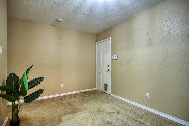 foyer with a textured ceiling, a textured wall, carpet flooring, and baseboards