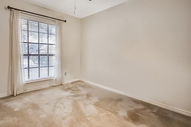 carpeted spare room with baseboards and a ceiling fan