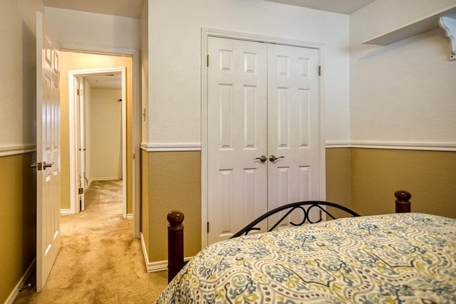 bedroom featuring baseboards, a closet, and light colored carpet