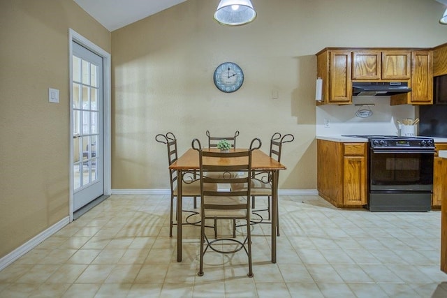 kitchen with brown cabinetry, baseboards, under cabinet range hood, and black stove