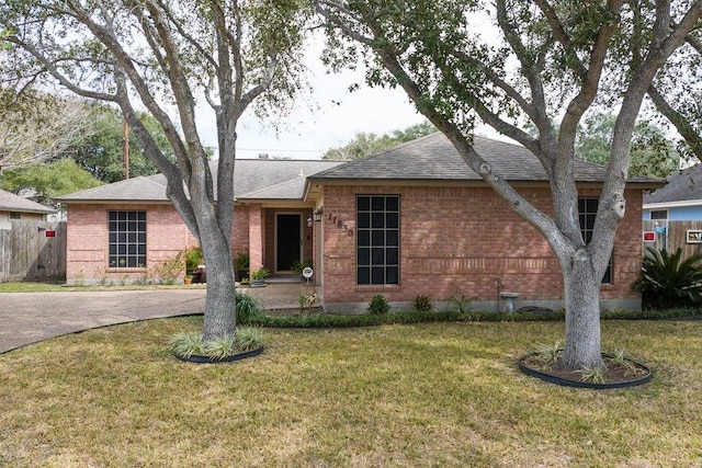 ranch-style house featuring a shingled roof, brick siding, and a front lawn