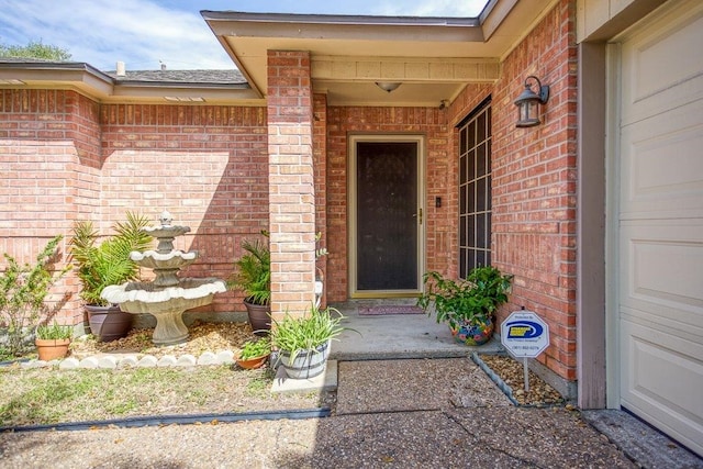 doorway to property featuring a garage and brick siding