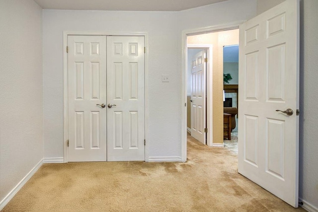 unfurnished bedroom with a closet, light carpet, and baseboards