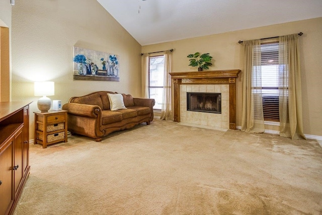 living room with high vaulted ceiling, a tile fireplace, a wealth of natural light, and light colored carpet