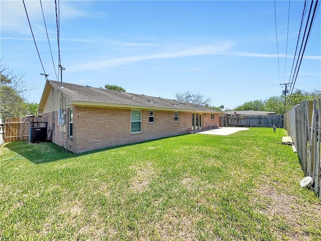 rear view of property featuring a lawn, a fenced backyard, a patio, central air condition unit, and brick siding