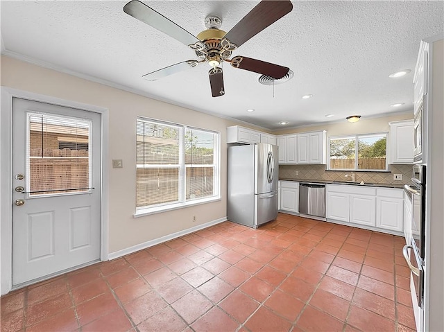 kitchen with tasteful backsplash, a ceiling fan, white cabinetry, appliances with stainless steel finishes, and a sink