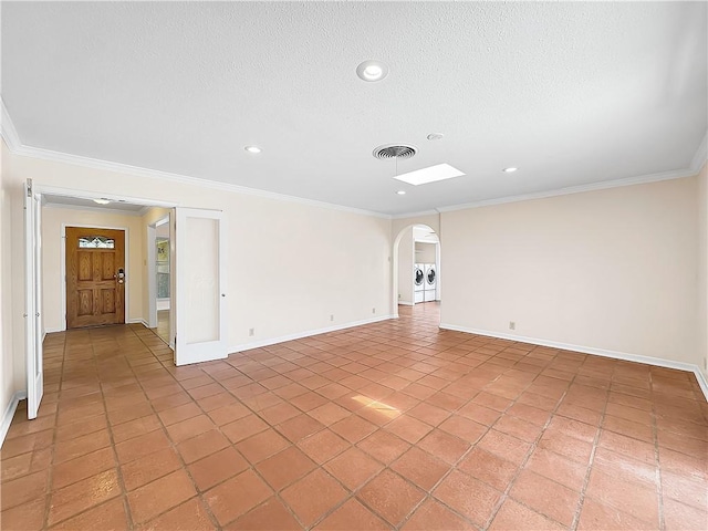 spare room featuring crown molding, arched walkways, a textured ceiling, visible vents, and washing machine and dryer