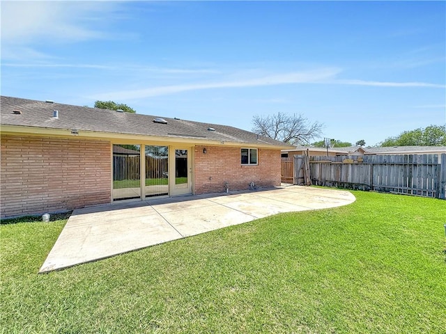 back of property with a patio area, fence, brick siding, and a yard