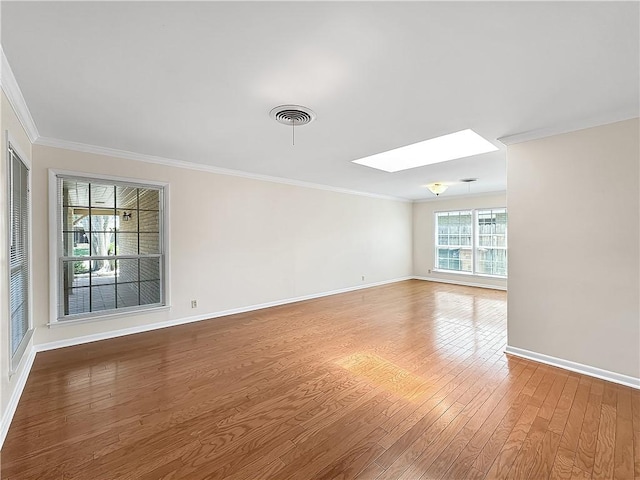 spare room featuring baseboards, crown molding, visible vents, a skylight, and wood finished floors