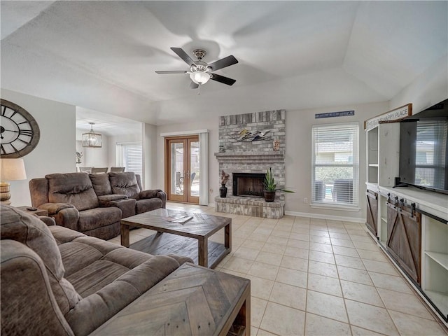living room featuring a raised ceiling, a ceiling fan, light tile patterned floors, a large fireplace, and baseboards