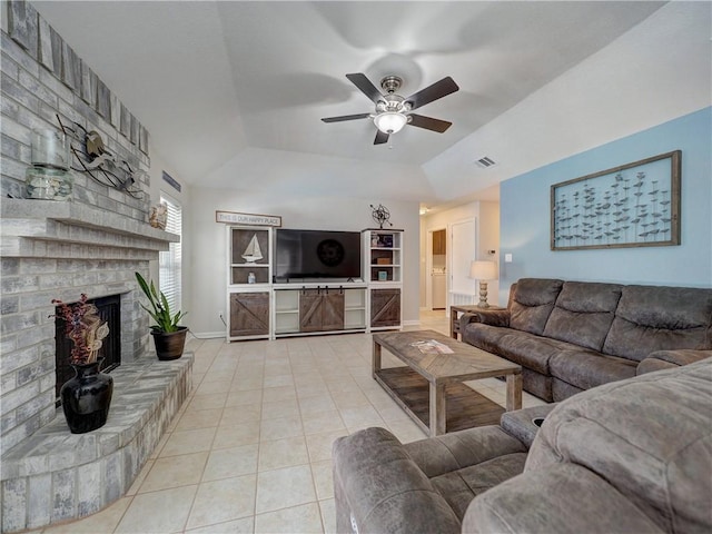 living area with a raised ceiling, tile patterned floors, ceiling fan, a brick fireplace, and baseboards