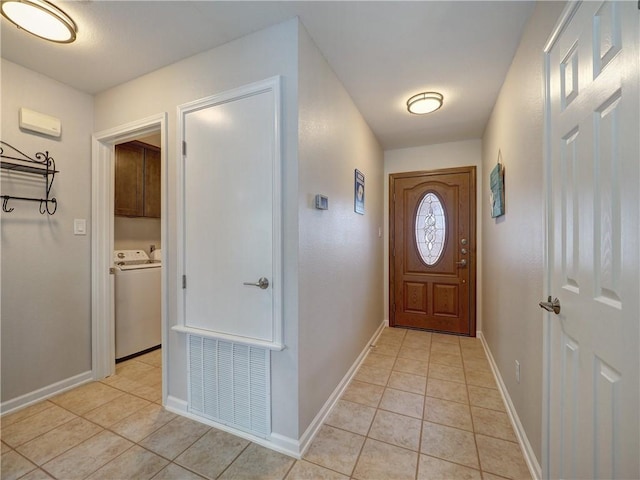 entryway with light tile patterned flooring, washer and clothes dryer, and baseboards