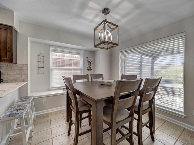 dining room featuring a chandelier, light tile patterned flooring, and baseboards