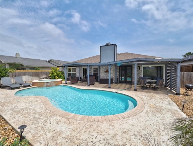 view of swimming pool with fence, french doors, a patio area, and a pool with connected hot tub
