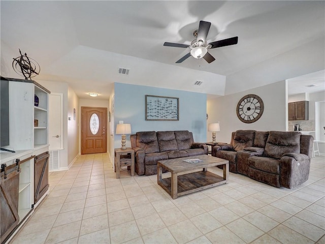 living area with light tile patterned flooring, ceiling fan, and a tray ceiling