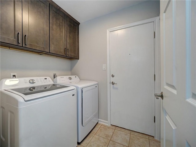 clothes washing area featuring cabinet space, washer and dryer, light tile patterned flooring, and baseboards