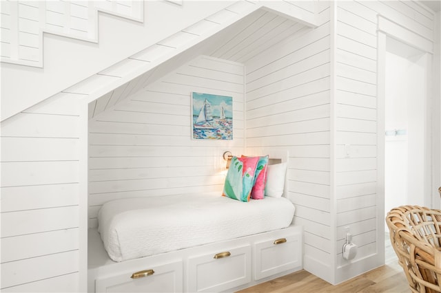 bedroom with wooden walls and light wood-style flooring