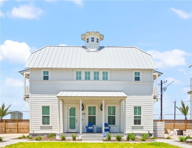 view of front of house featuring covered porch, a front yard, a standing seam roof, fence, and metal roof