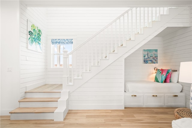 stairs with wood walls and wood finished floors