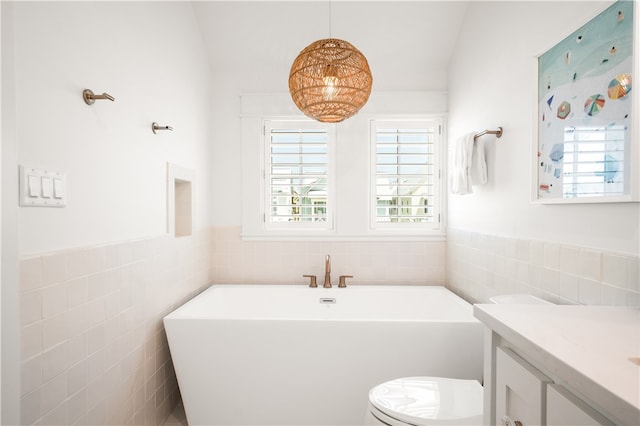 bathroom with toilet, a soaking tub, a wainscoted wall, and tile walls