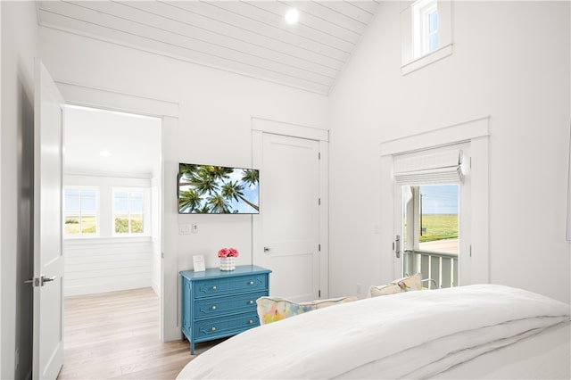 bedroom featuring lofted ceiling, access to outside, multiple windows, and light wood-type flooring
