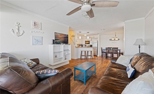 living room featuring ornamental molding, ceiling fan with notable chandelier, and hardwood / wood-style floors