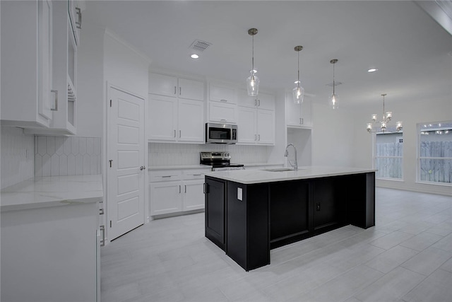 kitchen featuring stainless steel appliances, hanging light fixtures, white cabinetry, and decorative backsplash