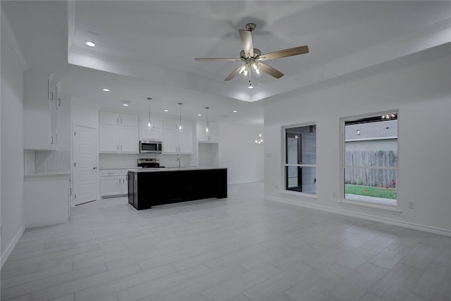 kitchen with stainless steel appliances, white cabinetry, a raised ceiling, hanging light fixtures, and a center island