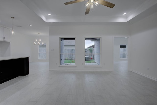 unfurnished living room featuring light wood-type flooring, ceiling fan with notable chandelier, crown molding, and a raised ceiling