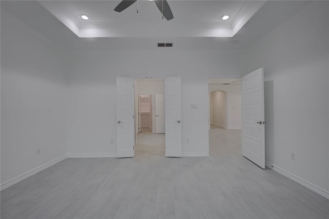 unfurnished bedroom with light hardwood / wood-style flooring, ceiling fan, and a raised ceiling