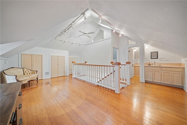 additional living space with sink, light hardwood / wood-style floors, vaulted ceiling, and ceiling fan