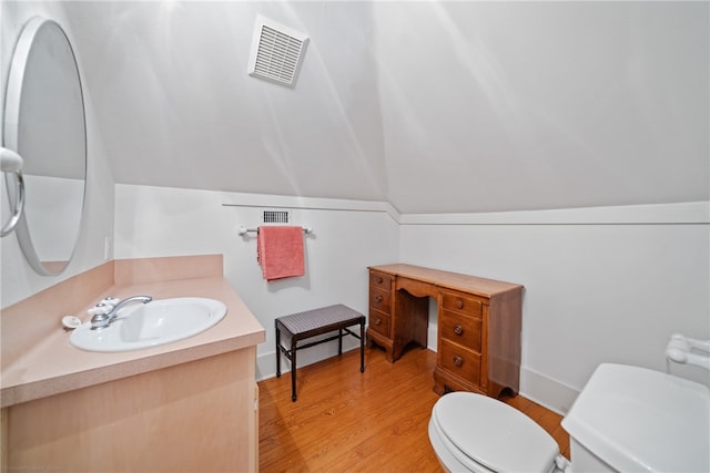 bathroom featuring hardwood / wood-style floors, lofted ceiling, toilet, and vanity