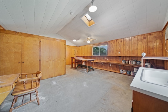 misc room with ceiling fan, wooden walls, sink, and lofted ceiling with skylight