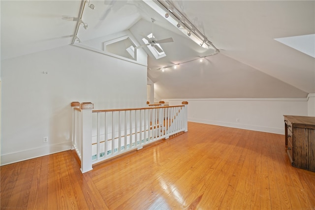 additional living space featuring hardwood / wood-style floors, ceiling fan, and vaulted ceiling with skylight