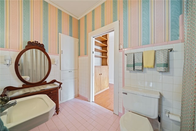 bathroom featuring sink, ornamental molding, tile patterned floors, toilet, and tile walls