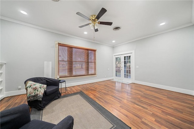 living area with wood-type flooring, ornamental molding, and ceiling fan