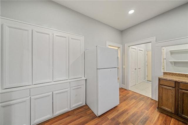 kitchen with white refrigerator, white cabinetry, and dark hardwood / wood-style flooring