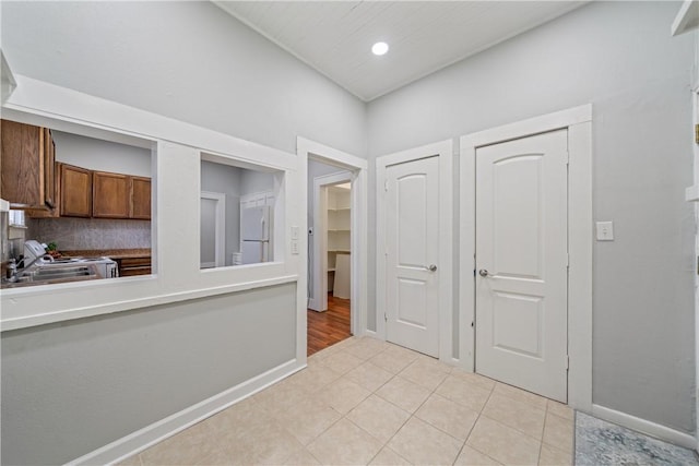 interior space featuring range, light tile patterned floors, white refrigerator, sink, and backsplash