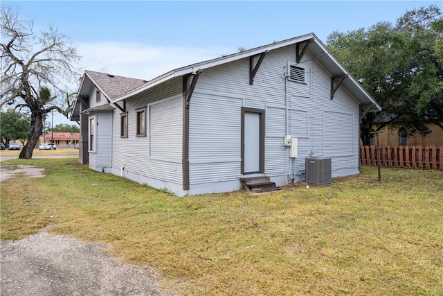 rear view of house featuring central air condition unit and a lawn