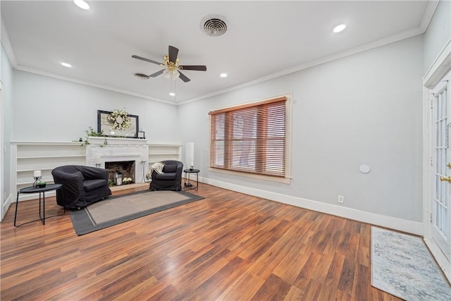 sitting room with ceiling fan, crown molding, and wood-type flooring