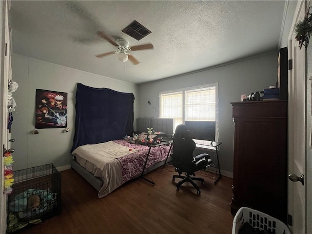 bedroom featuring wood finished floors, visible vents, a ceiling fan, baseboards, and a textured ceiling