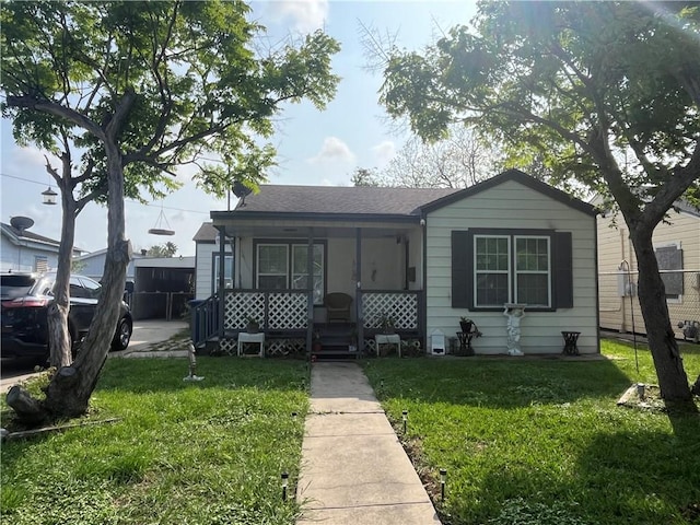 bungalow-style home with a porch, a shingled roof, and a front lawn