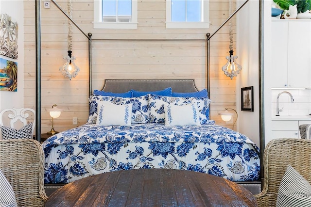 bedroom with wooden walls, multiple windows, and a sink