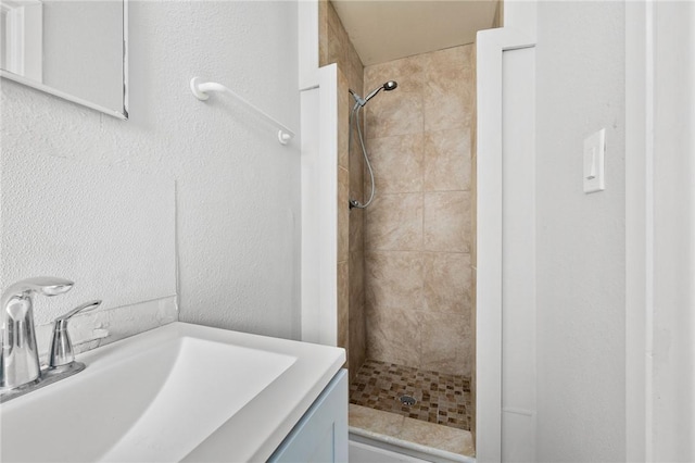 bathroom featuring tiled shower and vanity