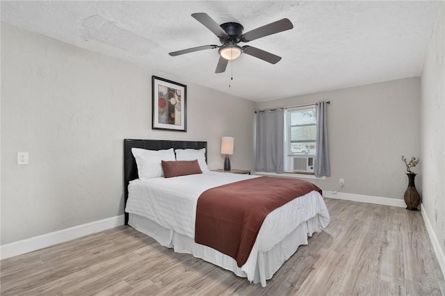 bedroom with ceiling fan, light hardwood / wood-style floors, and a textured ceiling