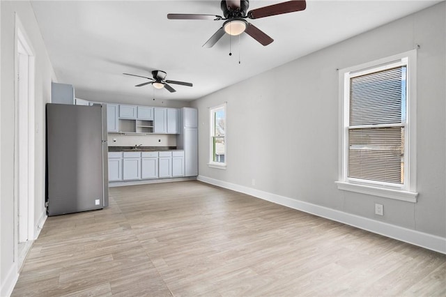 unfurnished living room featuring ceiling fan, sink, and light hardwood / wood-style floors