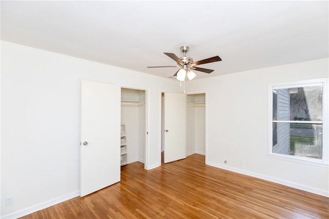 unfurnished bedroom featuring multiple closets, ceiling fan, and light hardwood / wood-style flooring