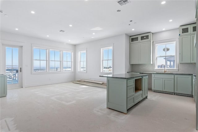 kitchen featuring recessed lighting, a sink, visible vents, backsplash, and dark countertops